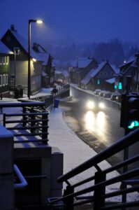 Schneebedeckte Straße in Clausthal-Zellerfeld im Oberharz bei Dämmerung mit verschneiten Häusern