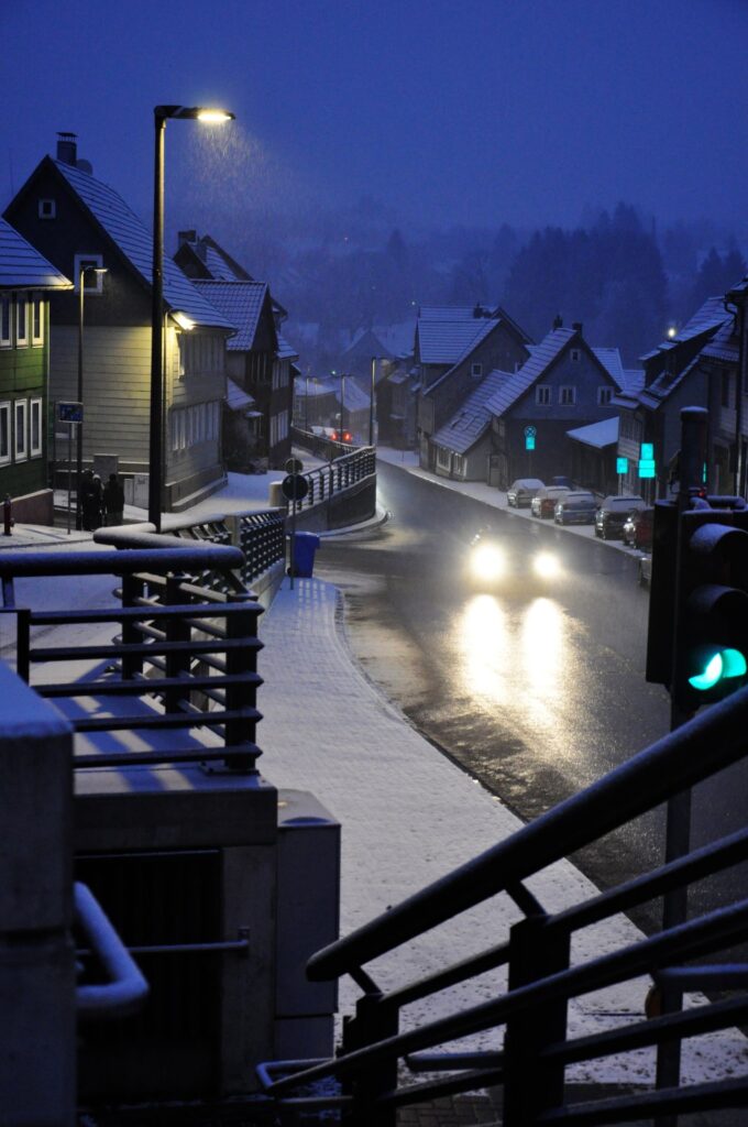 Schneebedeckte Straße in Clausthal-Zellerfeld im Oberharz bei Dämmerung mit verschneiten Häusern