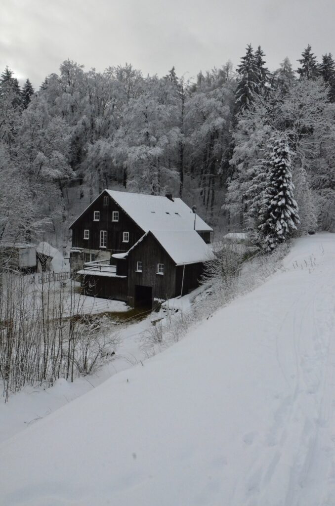 Dunkles Berghaus umgeben von schneebedeckter Winterlandschaft in Clausthal-Zellerfeld
