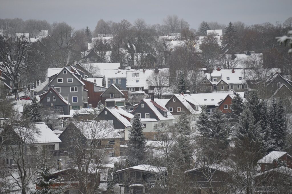 Schneebedecktes Bergdorf Clausthal-Zellerfeld mit roten und dunklen Häusern im Oberharz