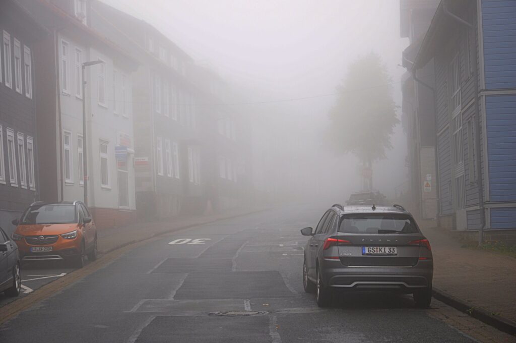 Neblige Straße in Clausthal-Zellerfeld mit parkenden Autos und historischen Gebäuden im Herbst