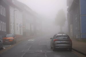 Neblige Straße in Clausthal-Zellerfeld mit parkenden Autos und historischen Gebäuden im Herbst