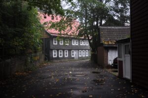 Altes Fachwerkhaus mit weißen Fensterläden in Clausthal-Zellerfeld, Herbstlaub auf Straße